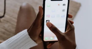 Pessoa segurando smartphone com aplicativos de redes sociais na tela, representando a importância do social media para empresas que desejam melhorar sua presença digital.